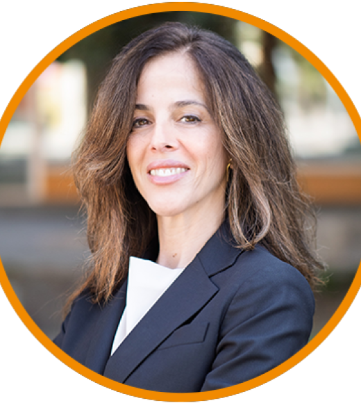 Professional headshot of a smiling woman in a dark blazer, orange circular border